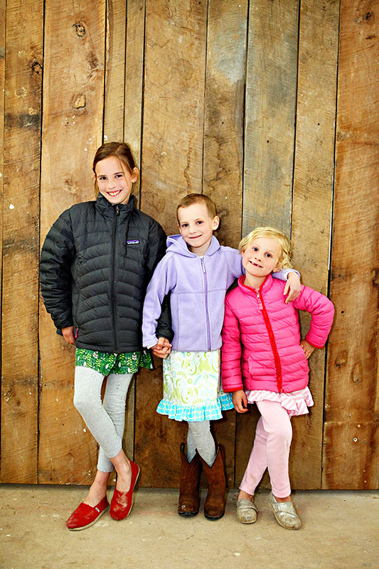 Southern Living Idea House St. Jude Ambassador Mae McNally and her sisters pose by the reclaimed sliding barn doors Castle Homes just installed as main house kitchen doors. (Photo by Sarah Lee)
